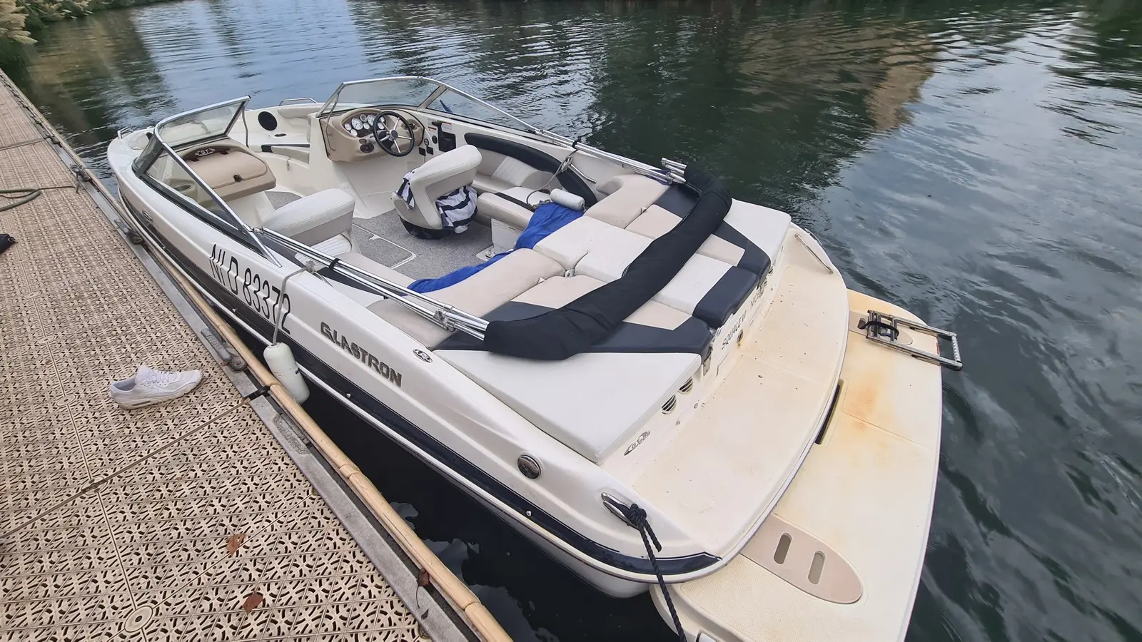 Glastron GT 225 — Bateau à moteur blanc amarré, vu en plongée trois quarts depuis le ponton.