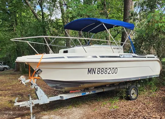 Guymarine GM 540 — Bateau à moteur blanc et bleu sur remorque, photographié à terre en sous-bois.
