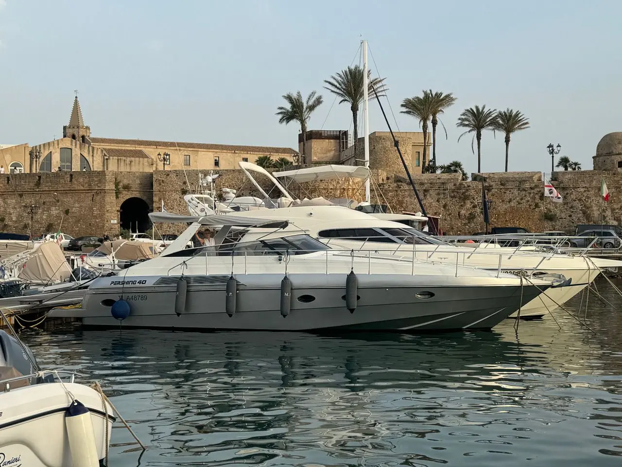 Pershing 40 — Bateau à moteur amarré dans un port, photographié de profil devant des remparts.