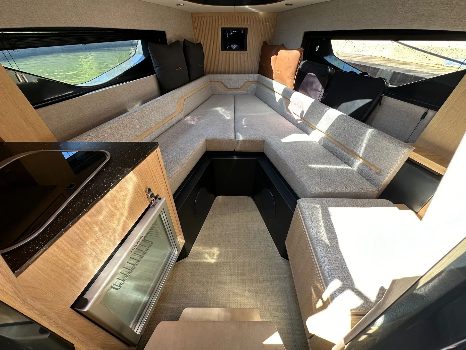 Flynt 956 — Salon intérieur avec banquettes, grandes fenêtres et meuble de cuisine.