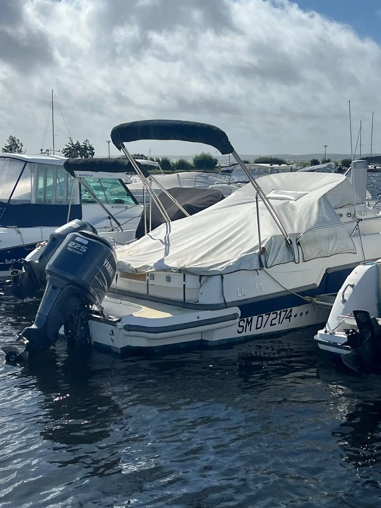Lexsia XS23 — Bateau à moteur vu de l’arrière, amarré au port et partiellement bâché.