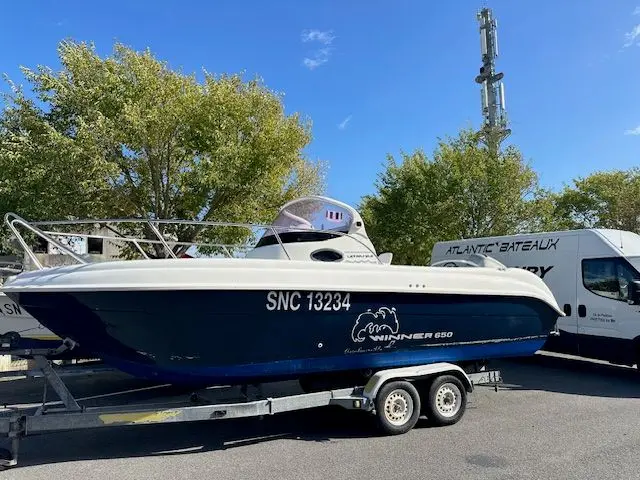 Ultramar 650 Winner — Bateau à moteur bleu et blanc posé sur une remorque, vu de trois quarts.