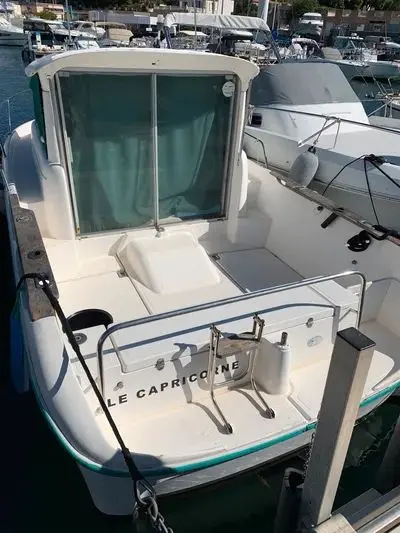 Ocqueteau 645 — Vue arrière d’un bateau blanc amarré dans une marina, avec cabine et plateforme arrière visibles.