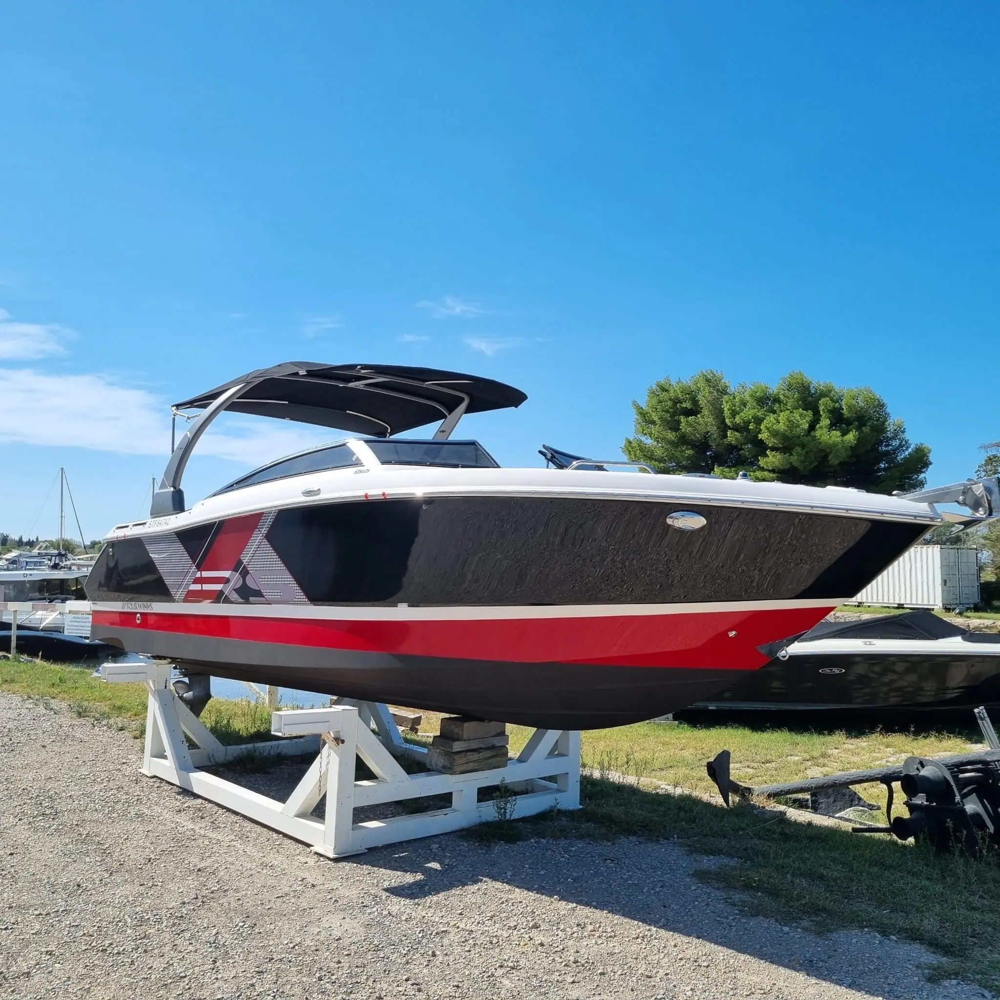 Four Winns Horizon 260 — Bateau à moteur rouge et noir photographié sur sa remorque, à terre.