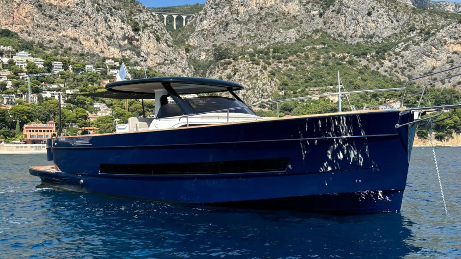 Apreamare Gozzo 45 — Bateau à moteur bleu photographié de profil dans une baie rocheuse.