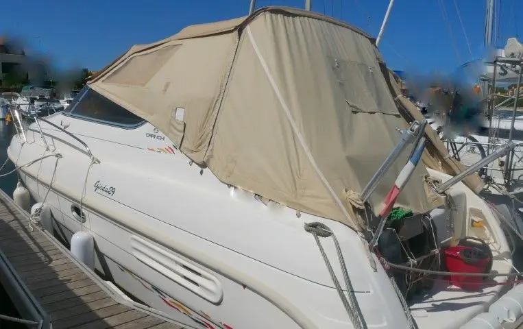 Cranchi Giada 29 — Bateau à moteur blanc amarré, vu de trois quarts arrière sous une bâche.