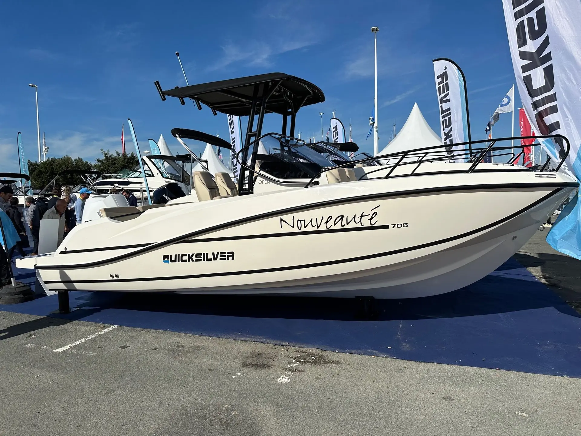 Quicksilver Activ 705 open — Bateau à moteur exposé en vue latérale sur un salon nautique.