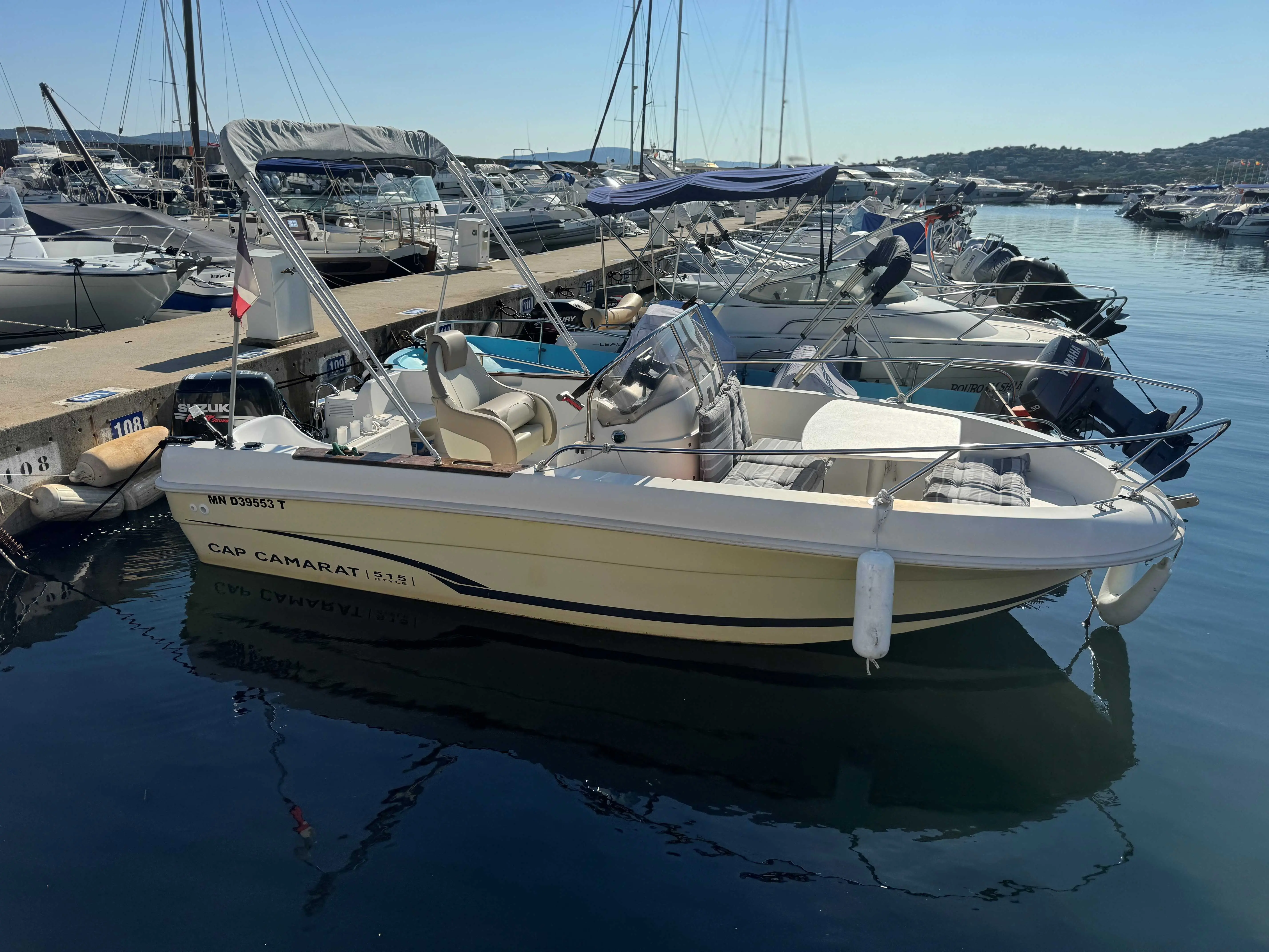 Jeanneau Cap Camarat 515 — Bateau à moteur blanc amarré dans un port, entouré d'autres embarcations.