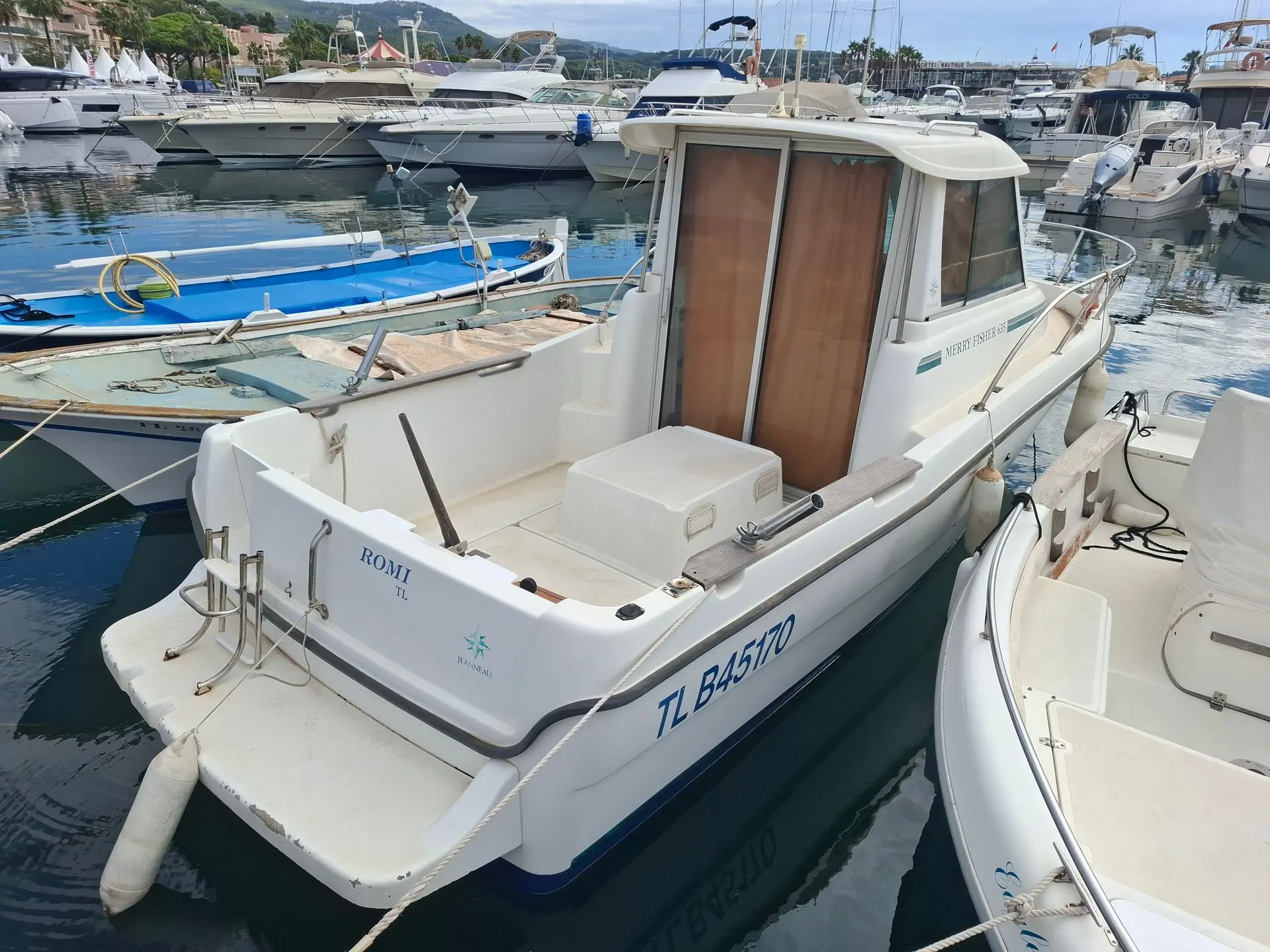 Jeanneau Merry Fisher 635 — Bateau à cabine amarré dans une marina, vu de trois quarts arrière.