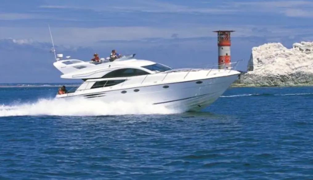 Fairline Phantom 50 — Vedette blanche en navigation devant un phare et une côte rocheuse.