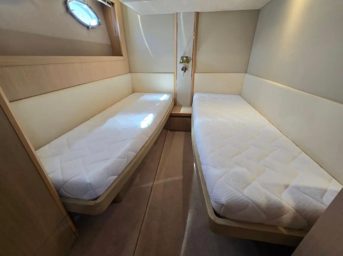 Princess V53 — Cabine avec deux couchettes simples, aménagement en bois et hublot latéral.