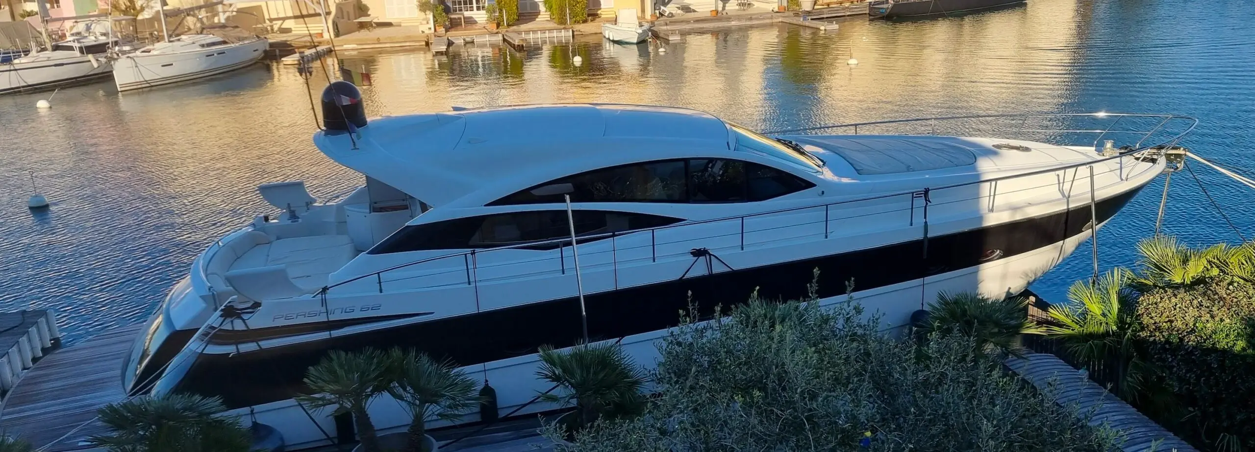 Pershing 62 — Bateau à moteur blanc amarré dans une marina, photographié en vue latérale.