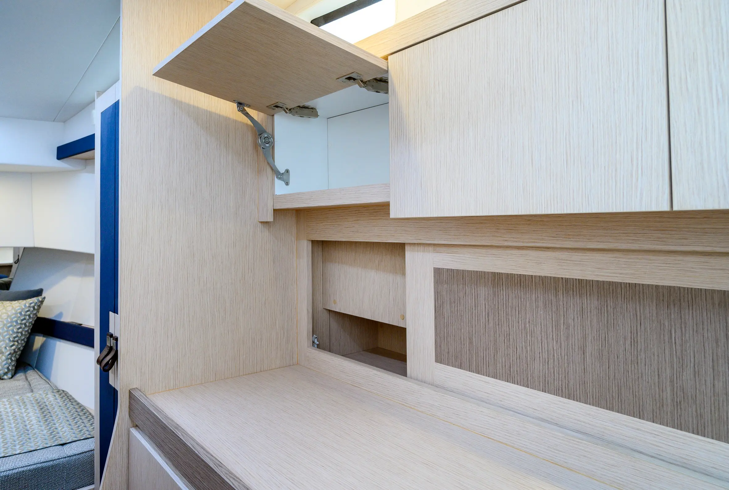 Apreamare Gozzo 35 — Vue rapprochée d’un aménagement en bois avec rangements et tablette relevable.