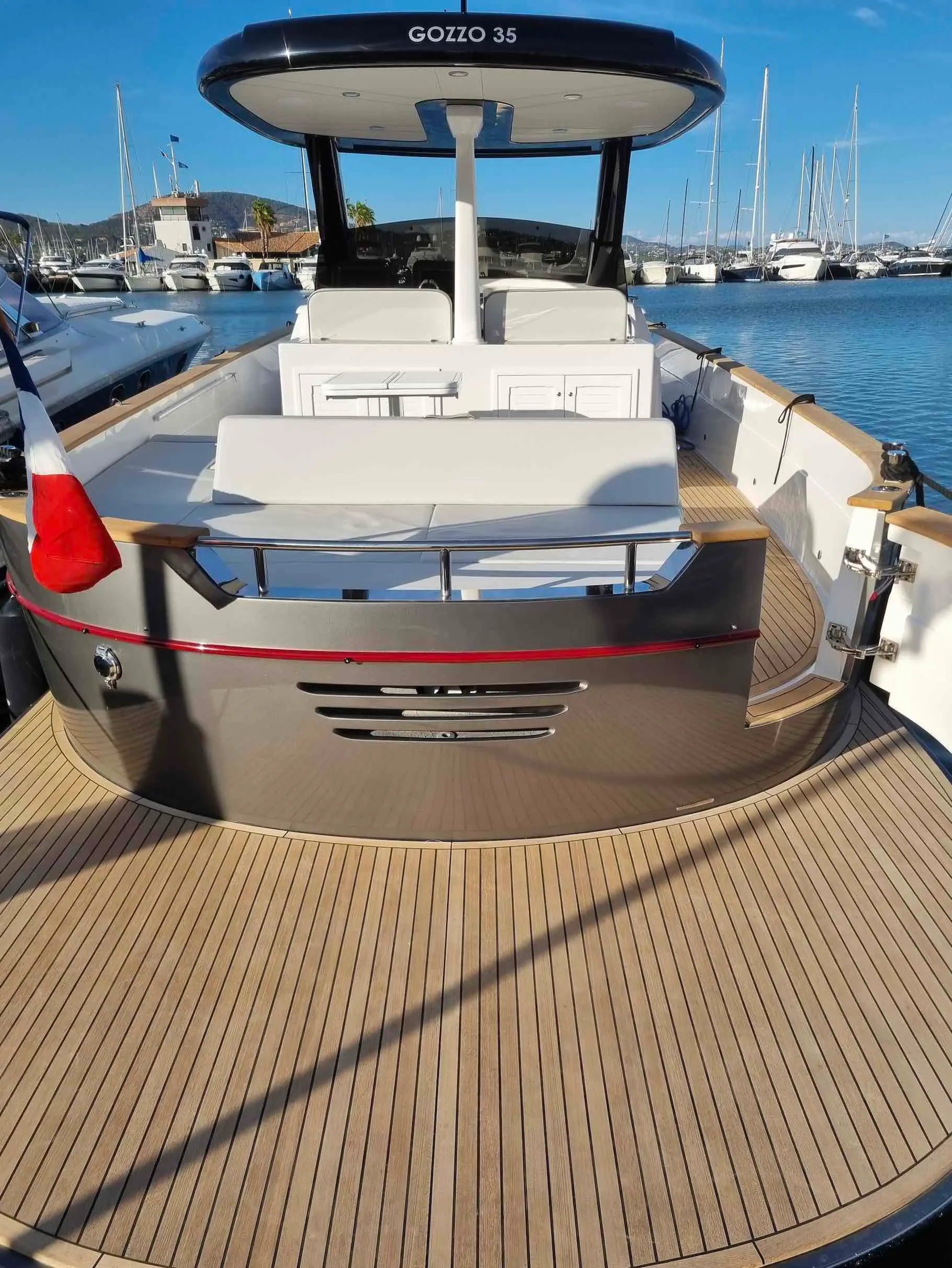Apreamare Gozzo 35 — Vue arrière du bateau avec bain de soleil et cockpit dans une marina.