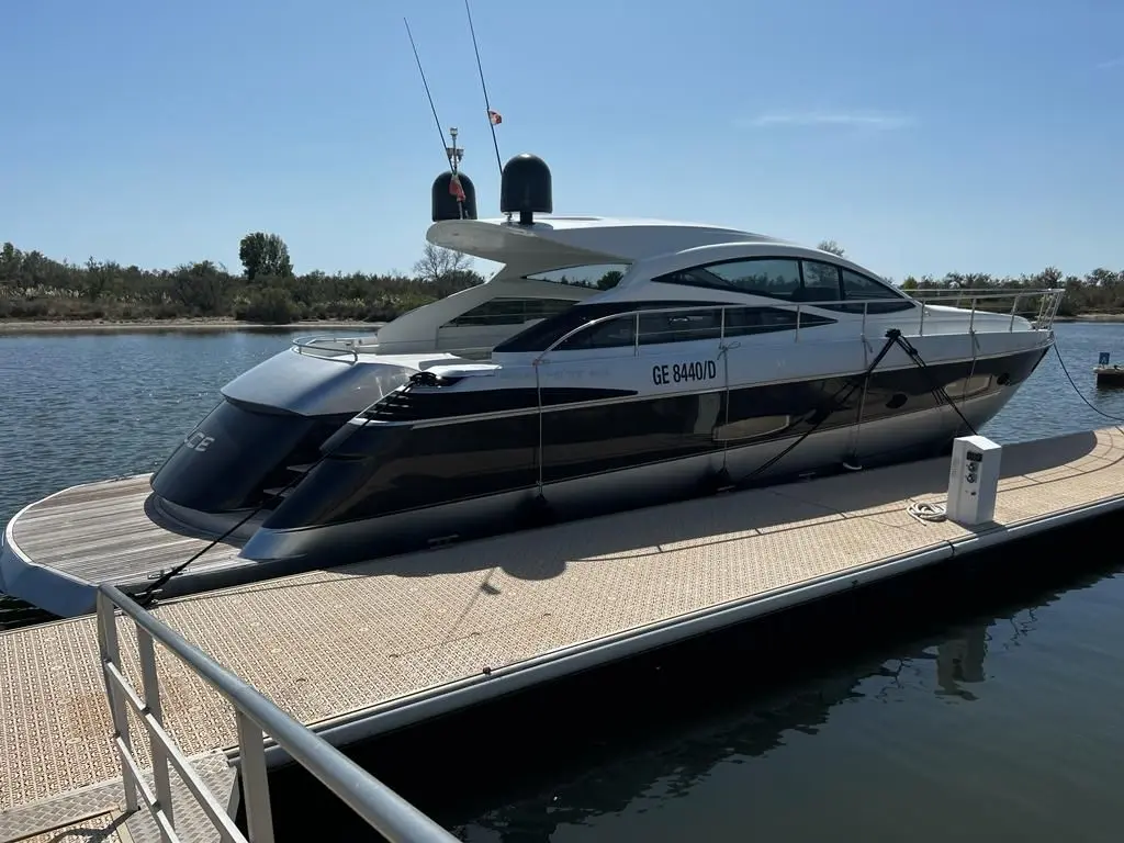Pershing 56 HT — Vedette à moteur blanche et noire amarrée à un ponton, vue de trois quarts.