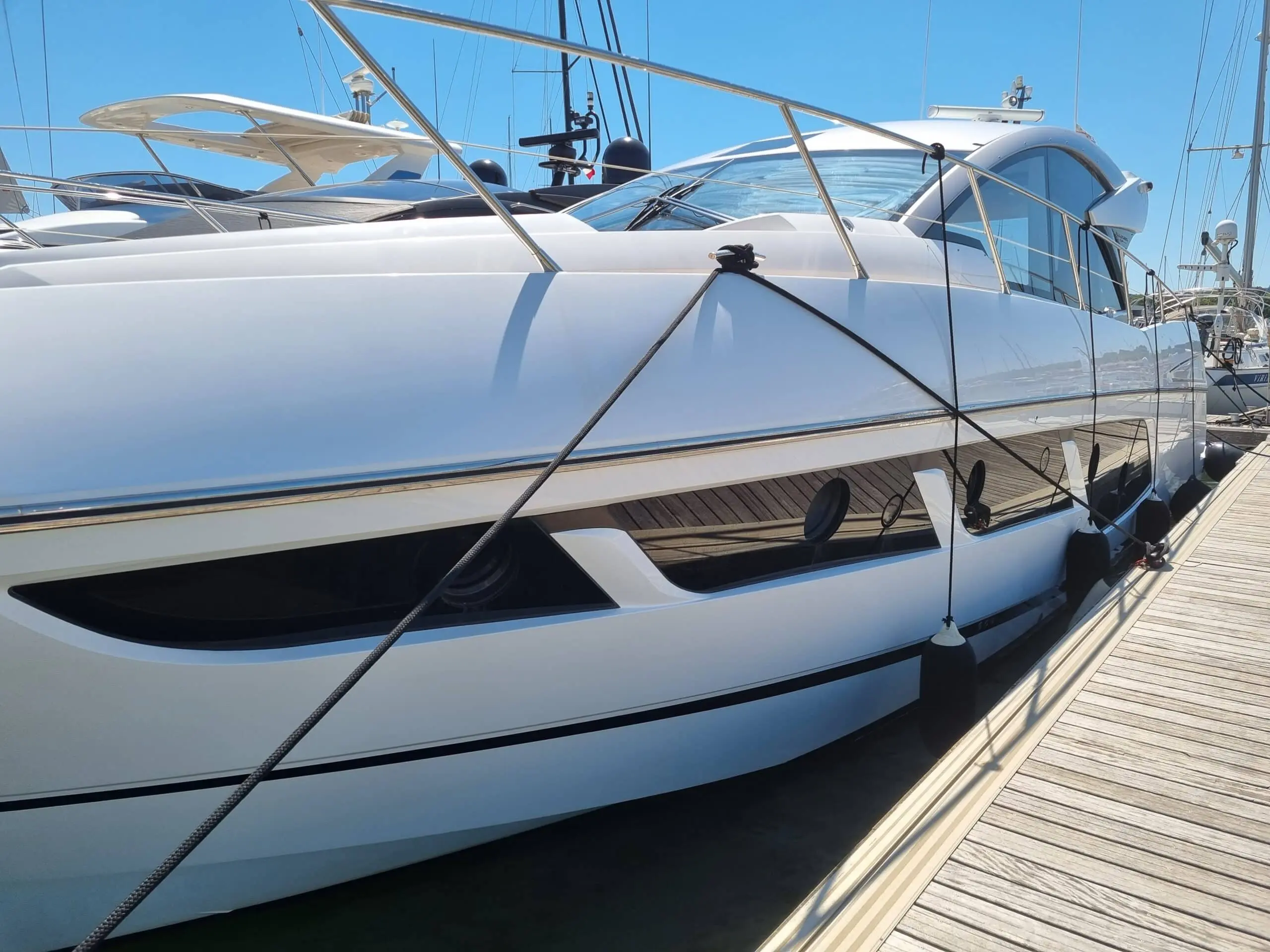 Sunseeker Predator 57 — Vue latérale d’un yacht blanc amarré dans une marina, prise depuis le ponton.