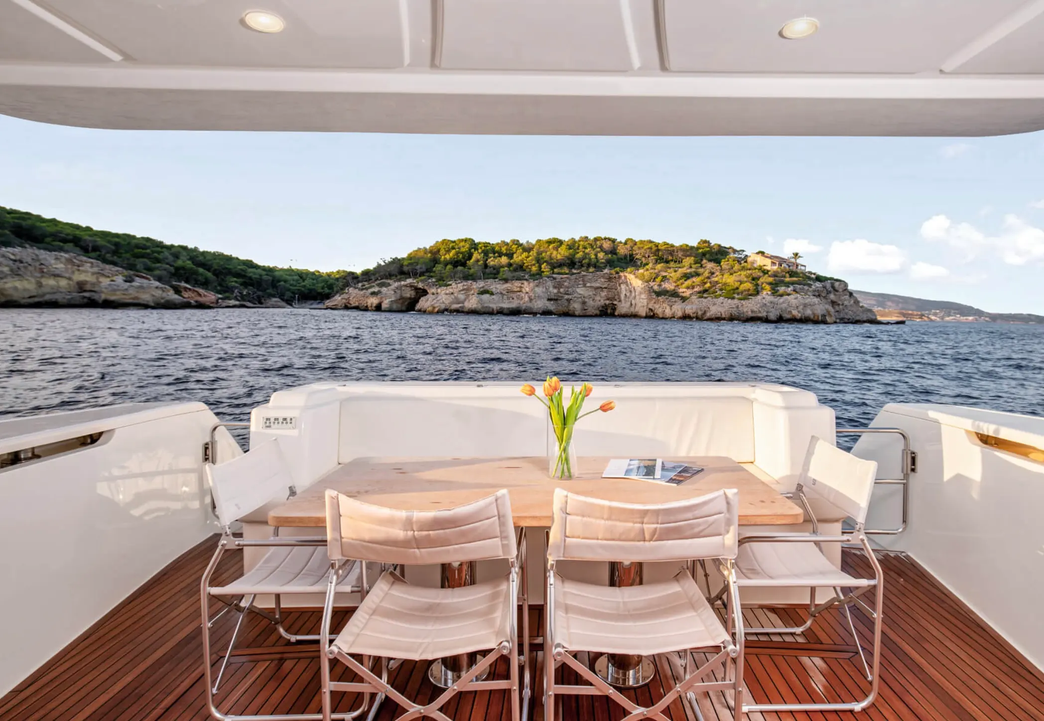 Ferretti 650 — Vue du cockpit arrière avec table, sièges et paysage côtier.