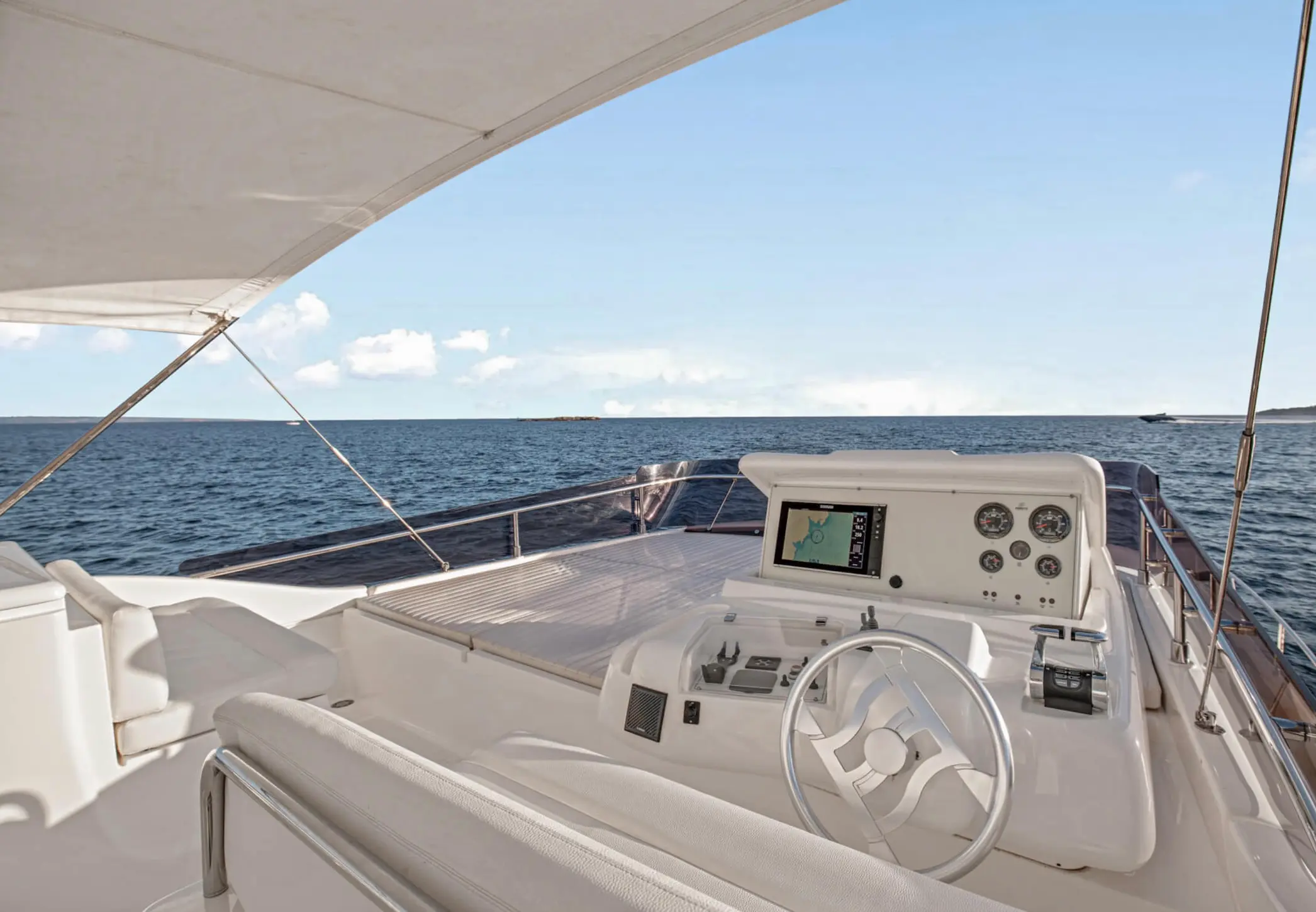 Ferretti 650 — Poste de pilotage extérieur avec tableau de bord, volant et vue sur la mer.