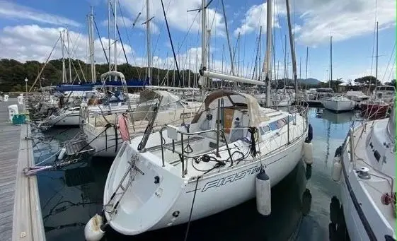 Beneteau First 285 — Voilier blanc amarré dans un port, vu de trois quarts arrière.