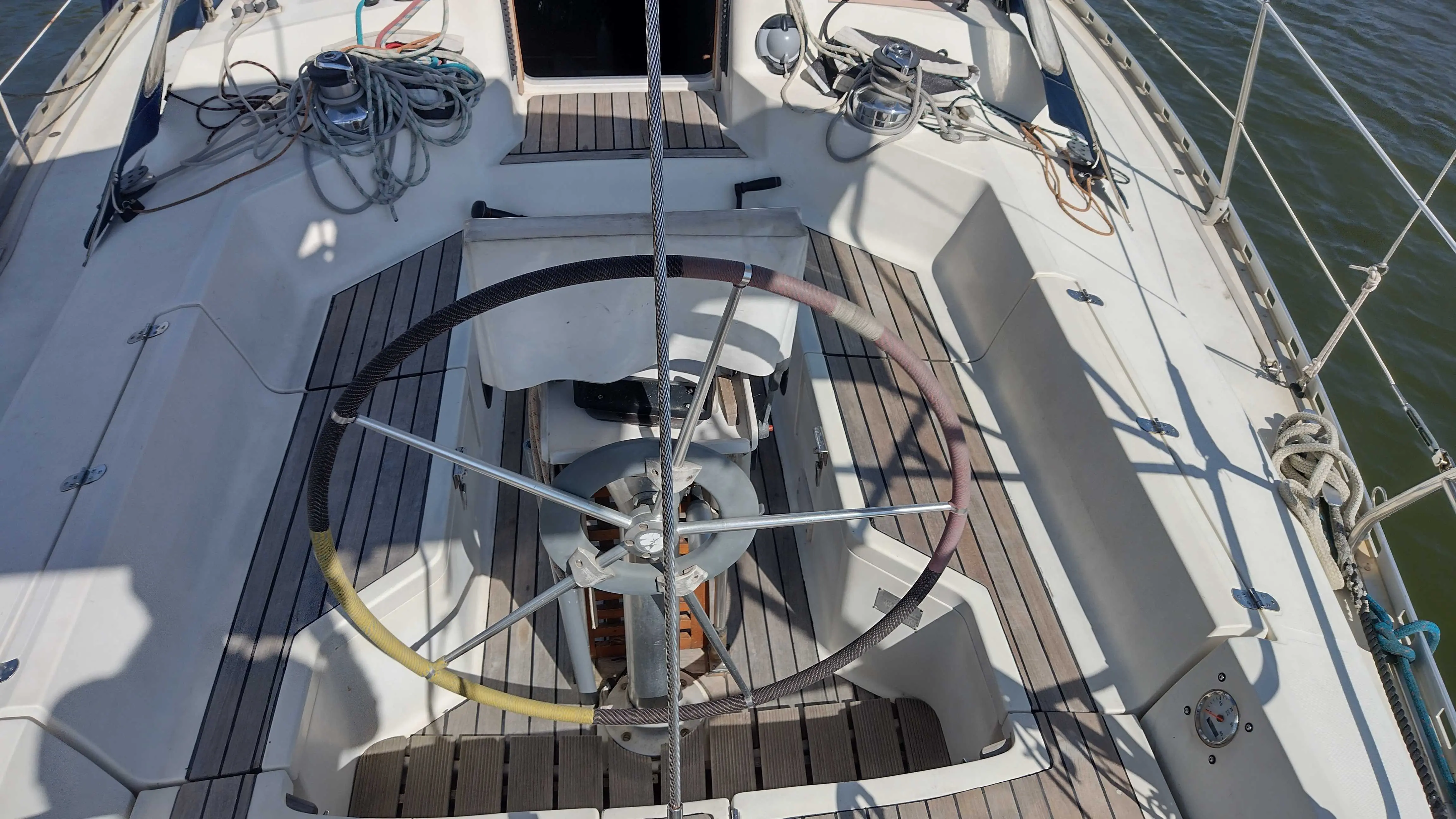 Gibert Marine Gib Sea 402 — Vue du cockpit d’un voilier avec barre à roue, pont en teck et cordages.