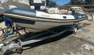 Zodiac Bombard Sunrider 650 — Bateau pneumatique blanc et bleu installé sur une remorque.