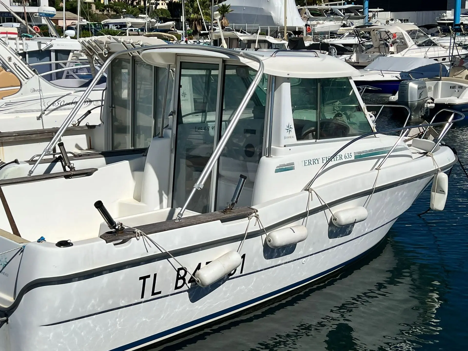 Jeanneau Merry Fisher 635 — Bateau à moteur blanc amarré dans un port, photographié de trois quarts avant.