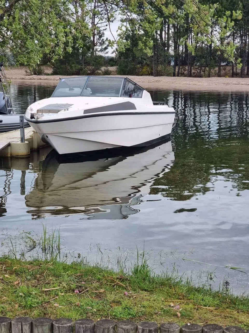 Rio 590 — Bateau à cabine blanche amarré à un ponton, vu de trois quarts avant.