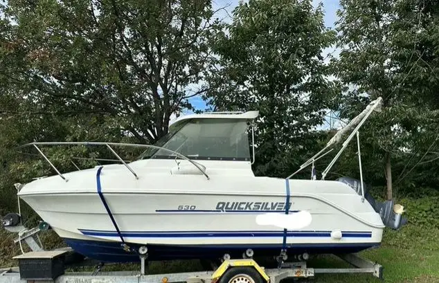 Quicksilver 530 — Bateau à moteur blanc présenté de profil sur une remorque, amarré par des sangles.