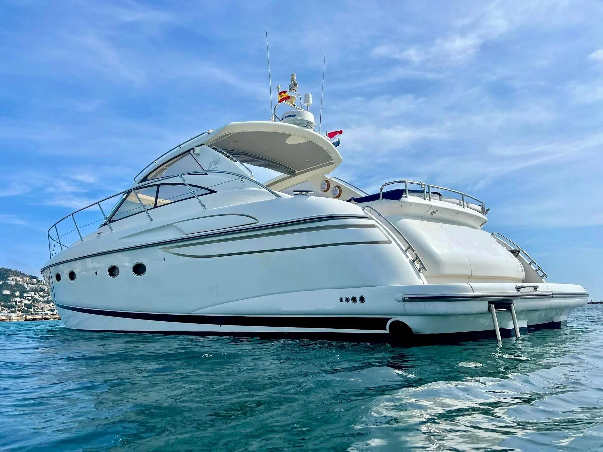 Princess V46 — Bateau à moteur blanc vu de trois quarts arrière, au mouillage dans une baie.