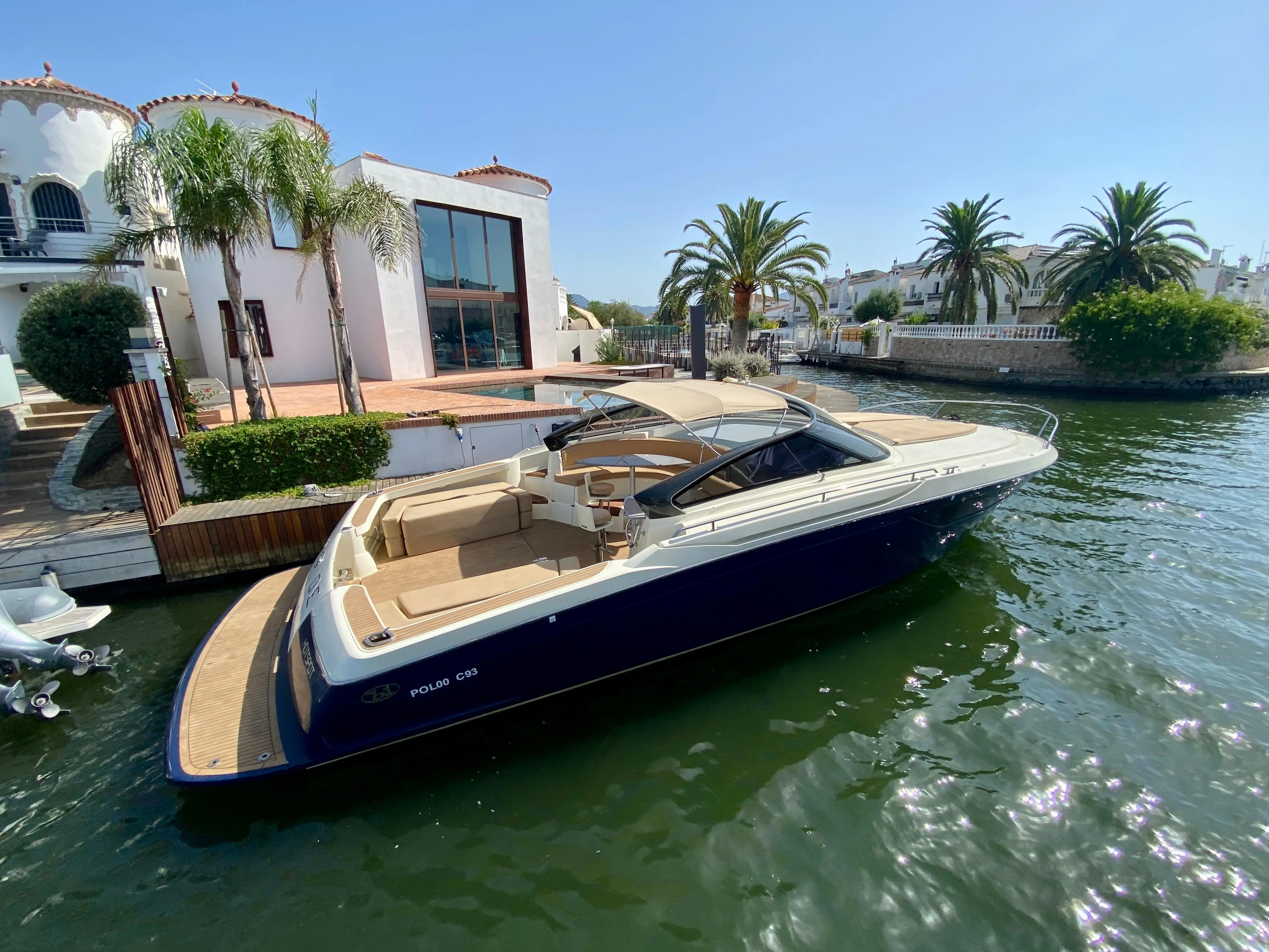 Baia One 43 — Bateau à moteur bleu et blanc amarré dans un canal résidentiel ensoleillé.