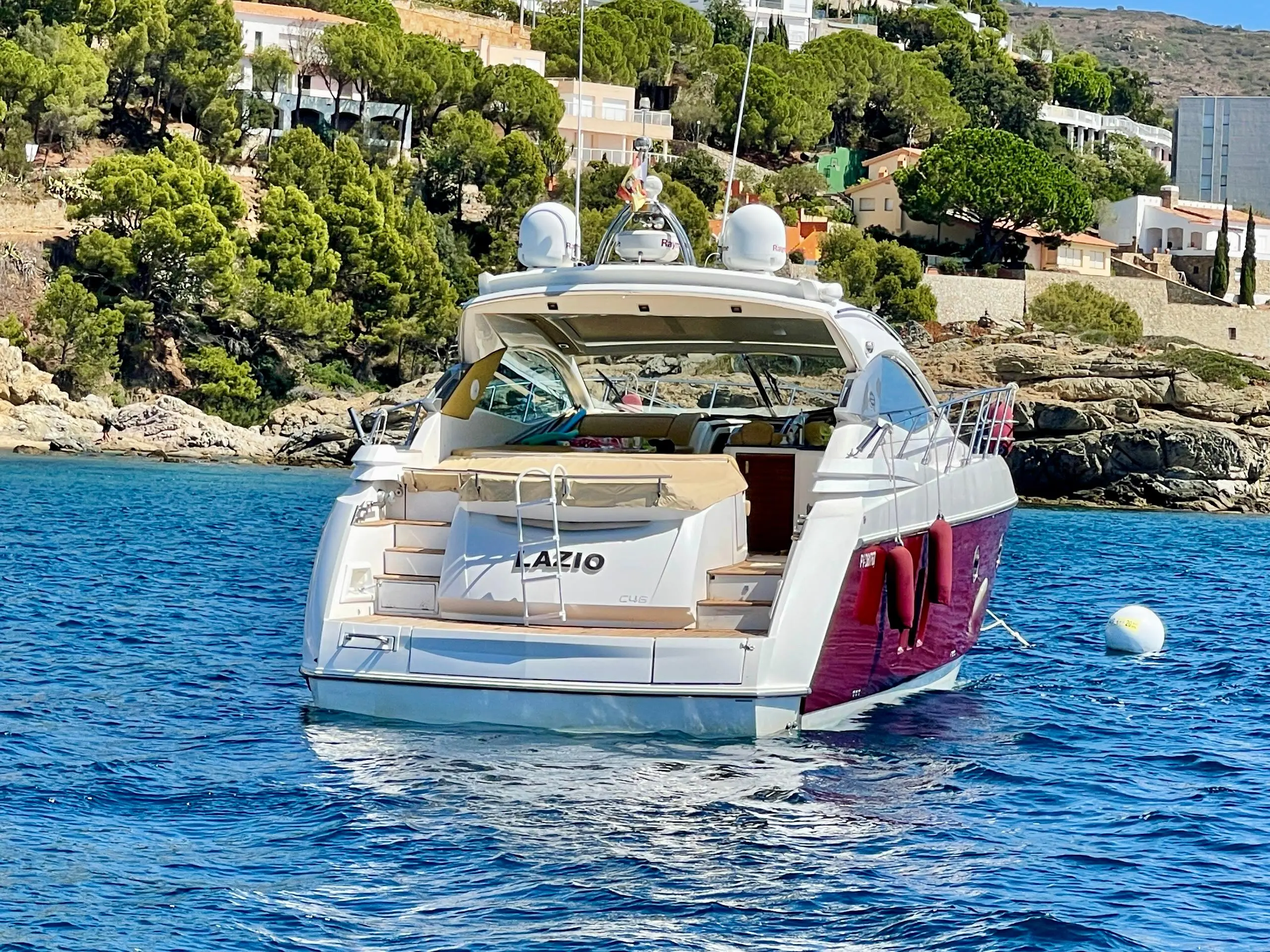 Sessa Marine C46 — Bateau à moteur blanc et bordeaux vu de trois quarts arrière dans une baie.