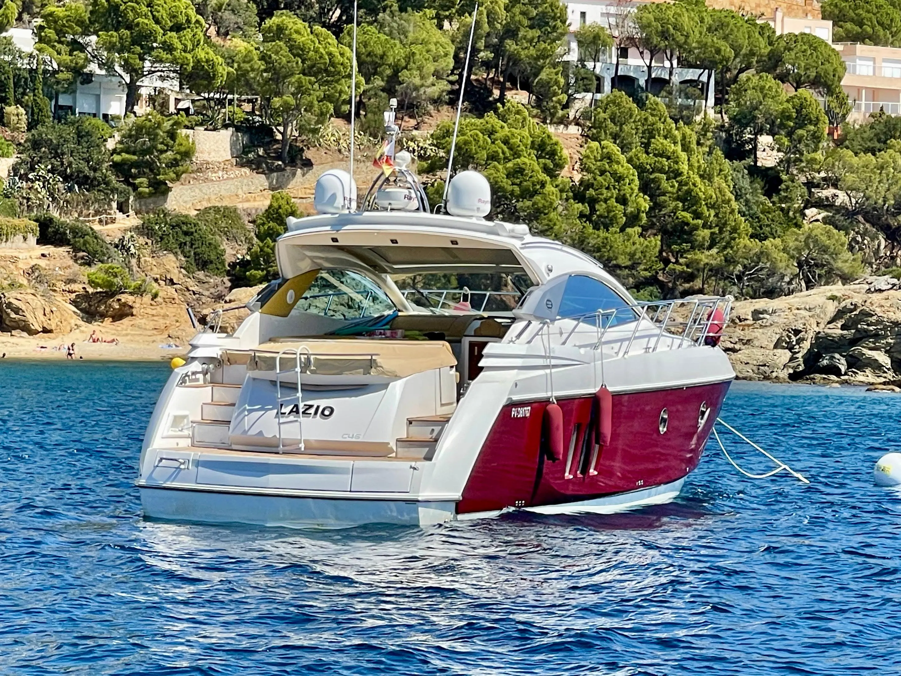 Sessa Marine C46 — Bateau à moteur blanc et bordeaux vu de trois quarts arrière dans une baie.