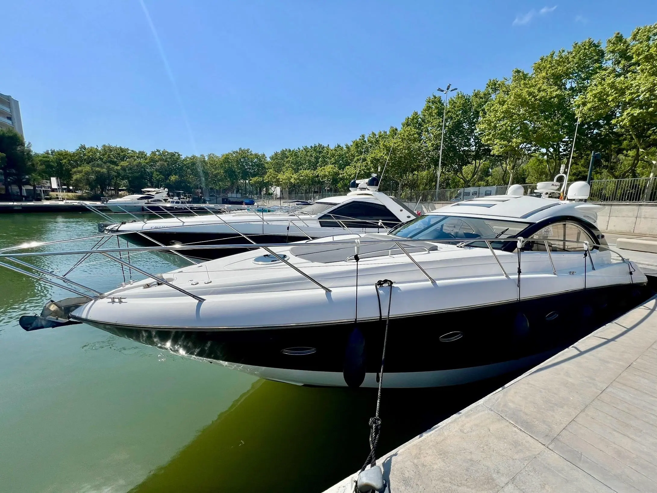 Sunseeker Portofino 47 — Bateau à moteur blanc et noir amarré dans un port, vu de trois quarts.