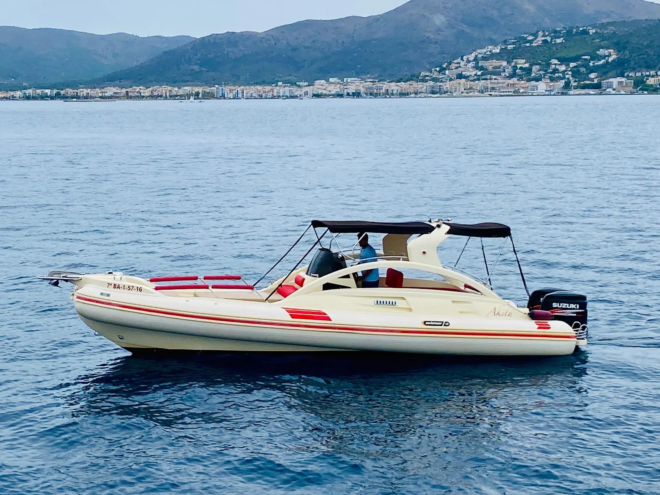 Solemar Offshore 28 — Bateau semi-rigide vu de profil sur l’eau, avec une côte habitée en arrière-plan.