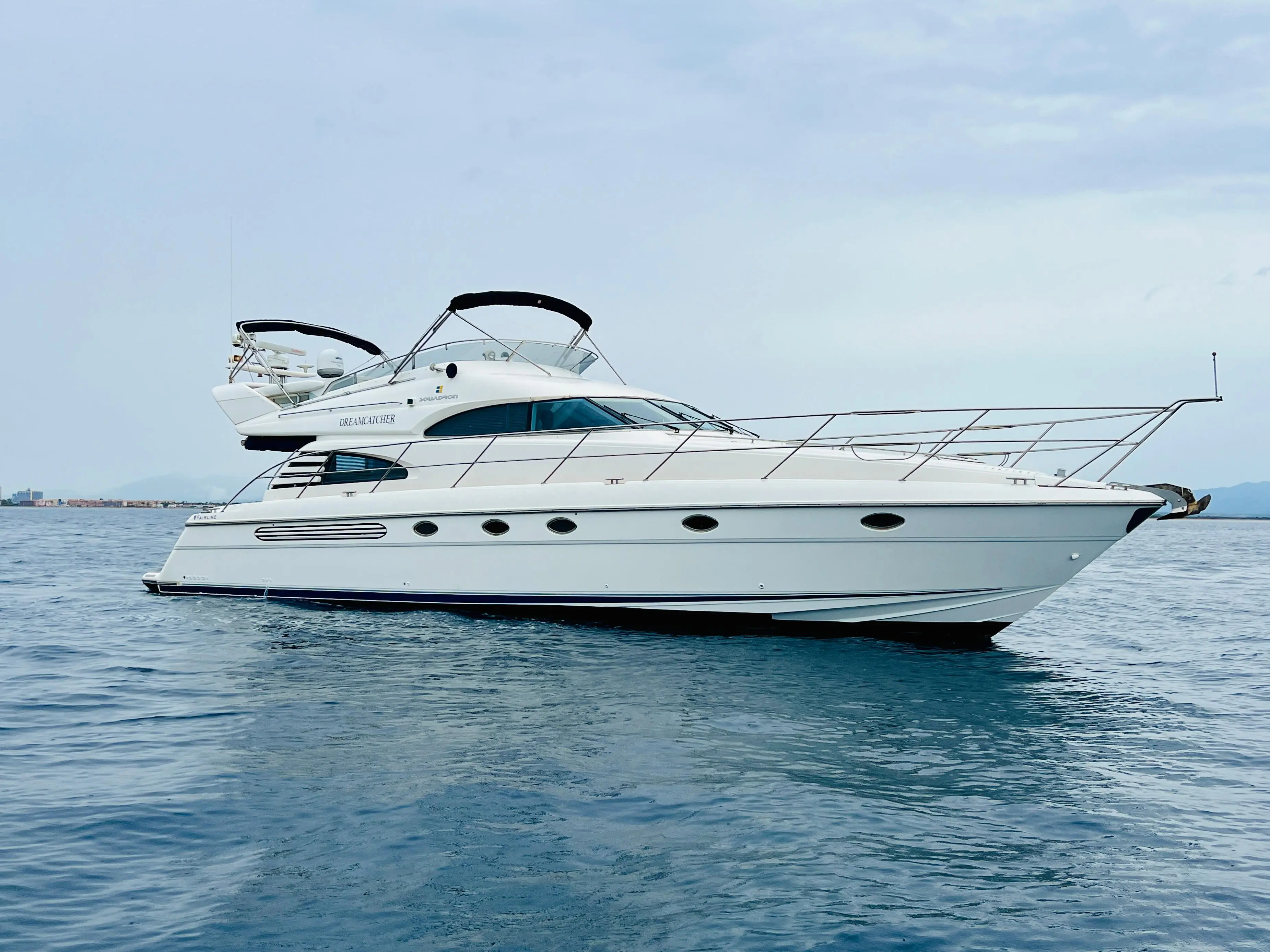 Fairline Squadron 55 — Vue latérale d’un yacht blanc à flybridge naviguant sur une mer calme.