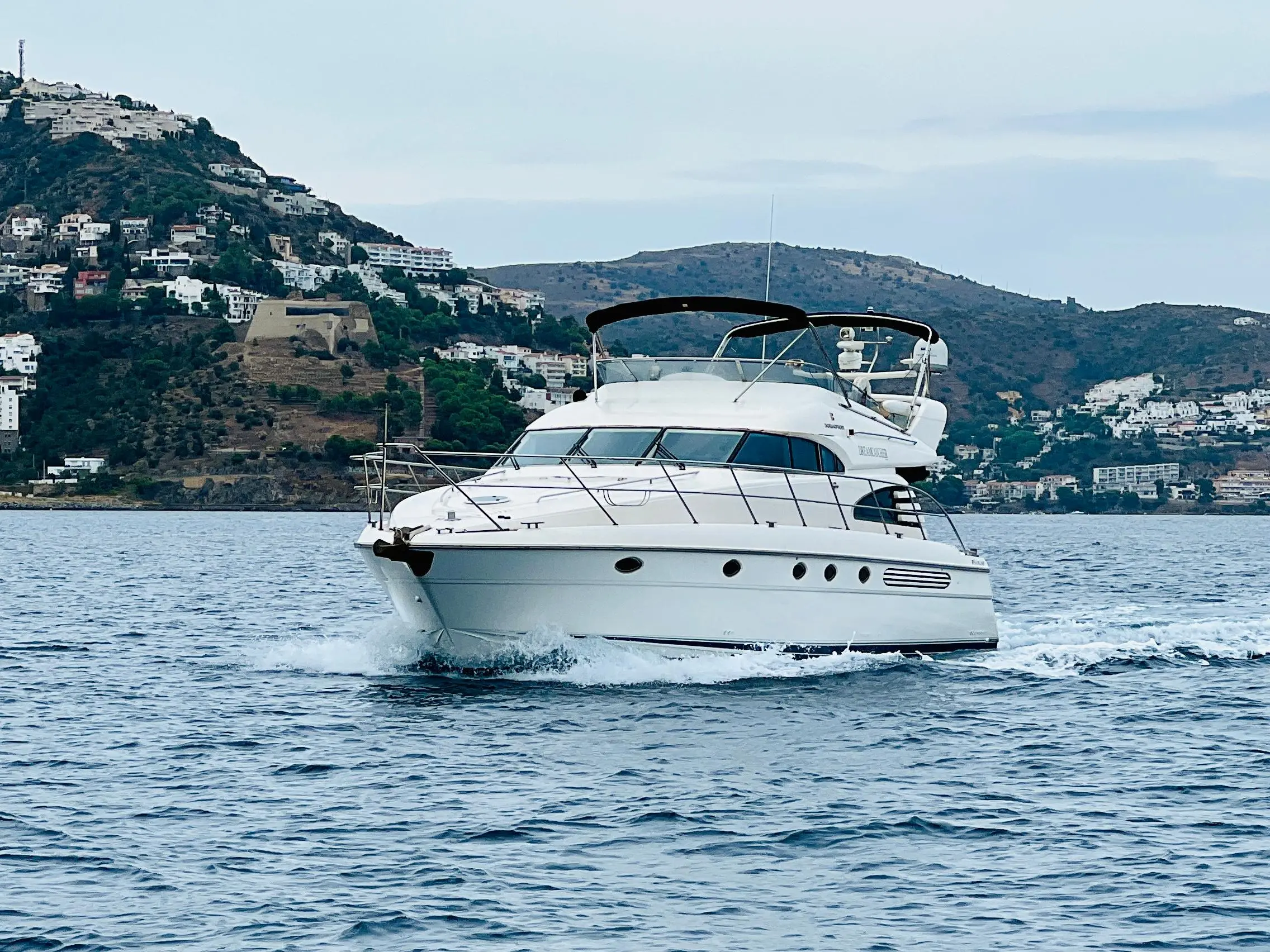 Fairline Squadron 55 — Vedette à moteur blanche naviguant devant un paysage côtier vallonné