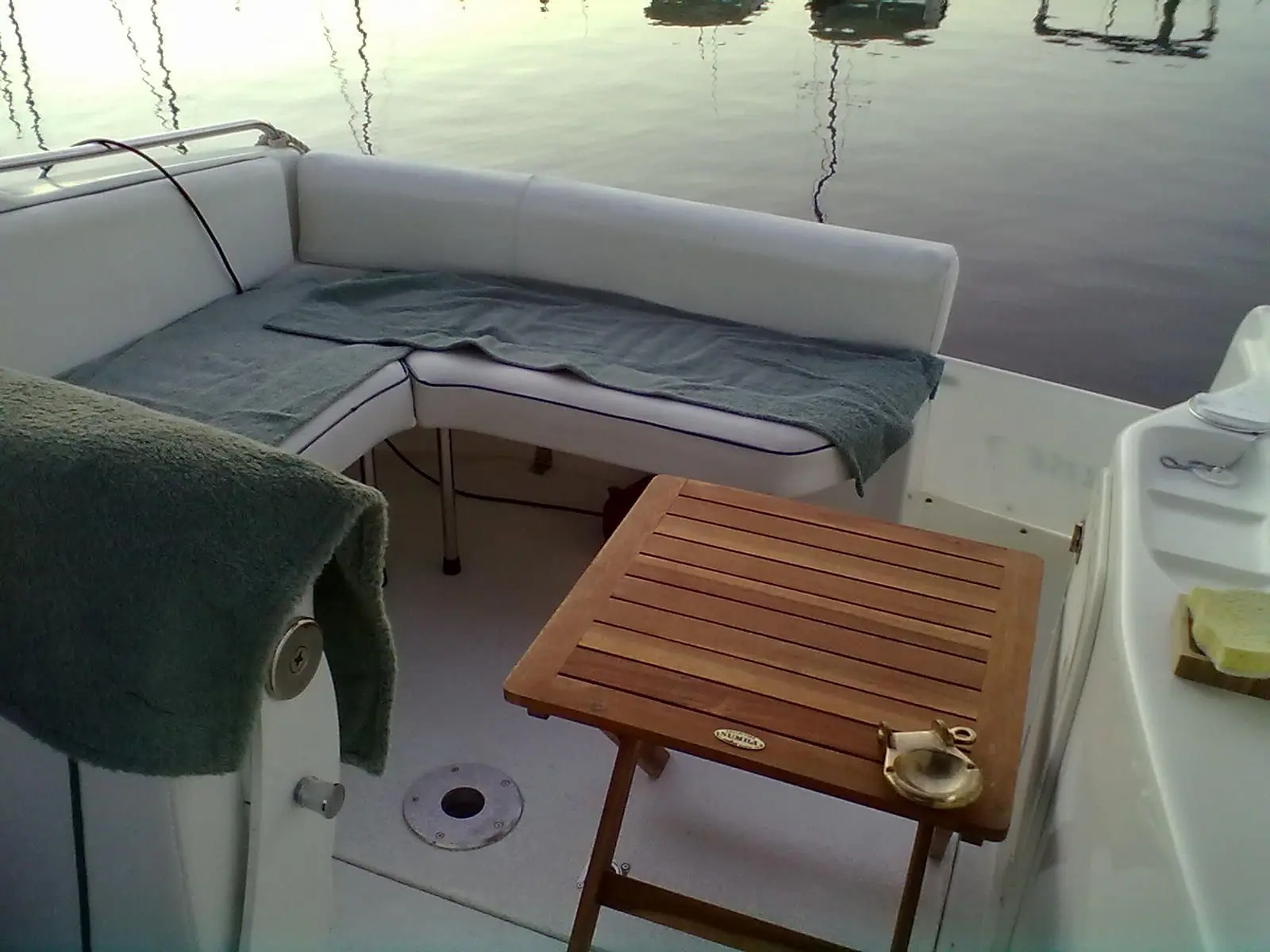 Sessa Marine Oyster 22 — Vue du cockpit arrière avec banquette, table en bois et accès à la barre.