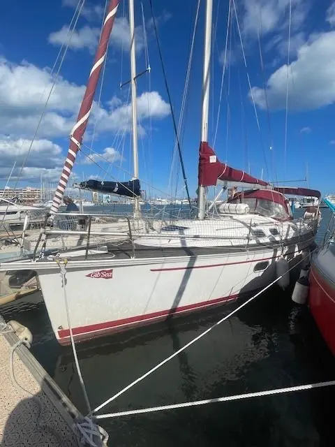 Gib Sea 33 — Voilier blanc amarré dans un port, vu de trois quarts avec les voiles ferlées.