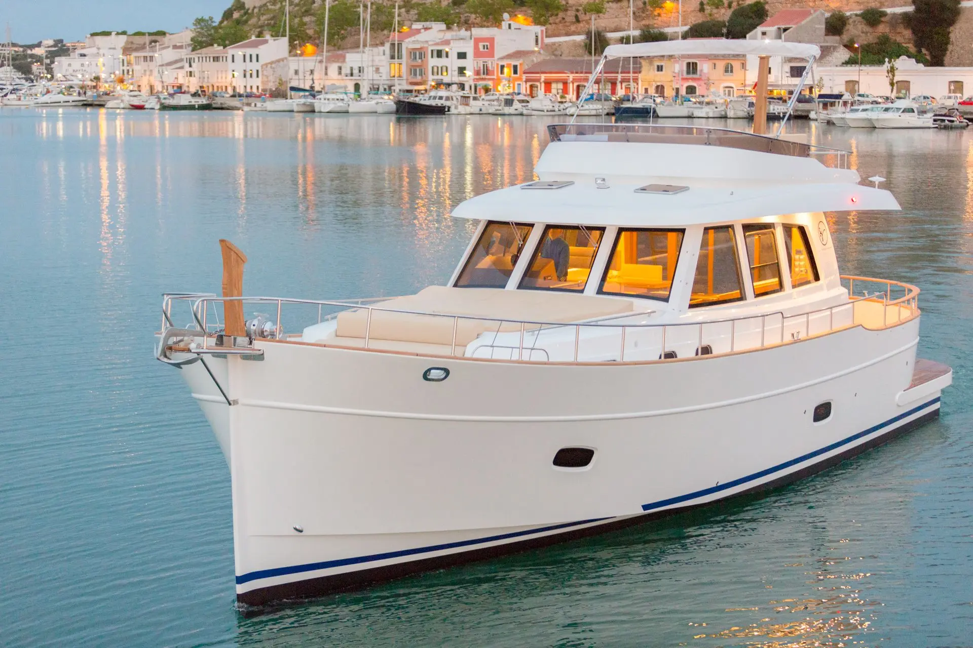 Sasga Menorquin 55 — Bateau à moteur blanc vu de trois quarts dans un port au coucher du soleil.