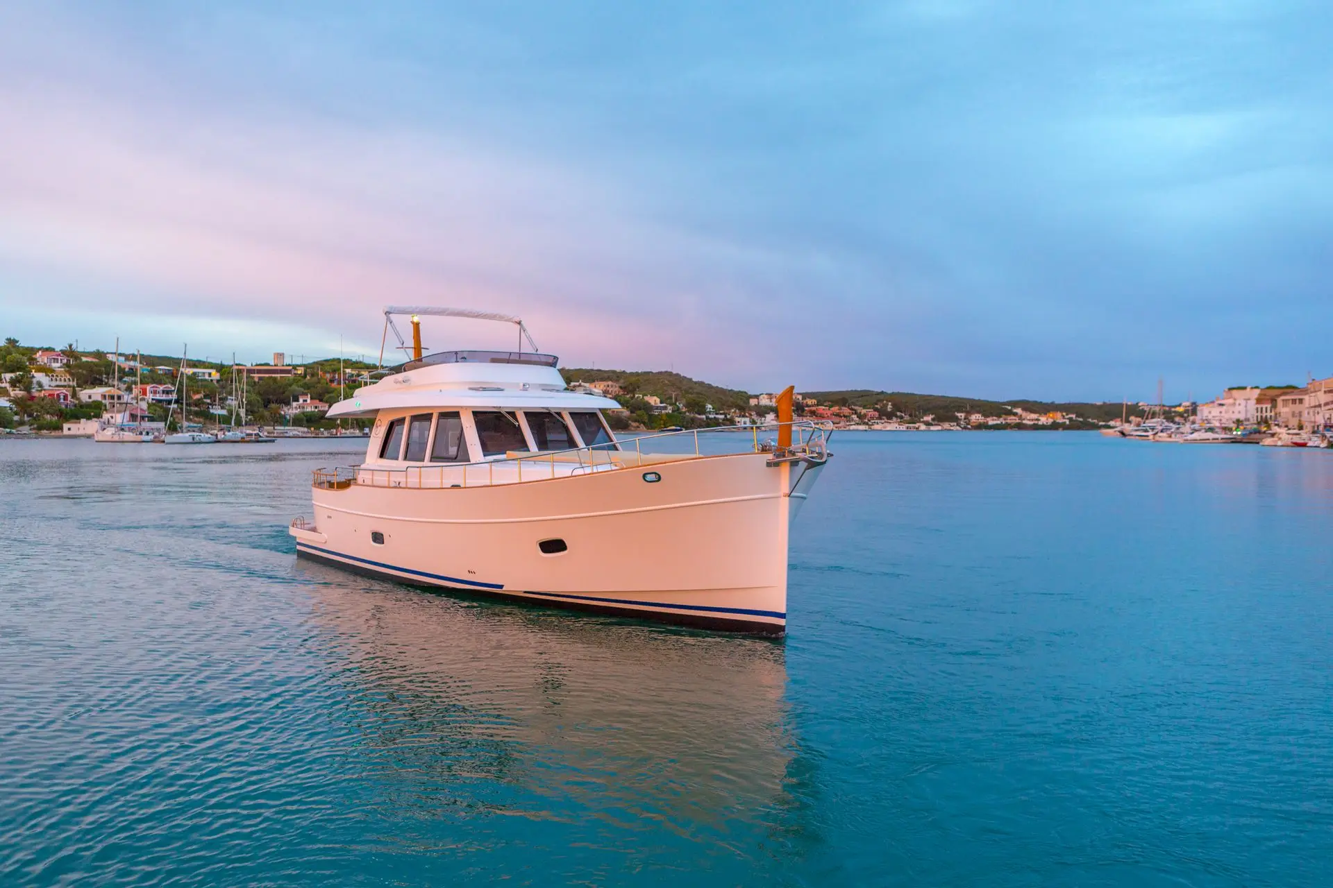Sasga Menorquin 55 — Bateau à moteur blanc vu de trois-quarts dans un port au coucher du soleil.