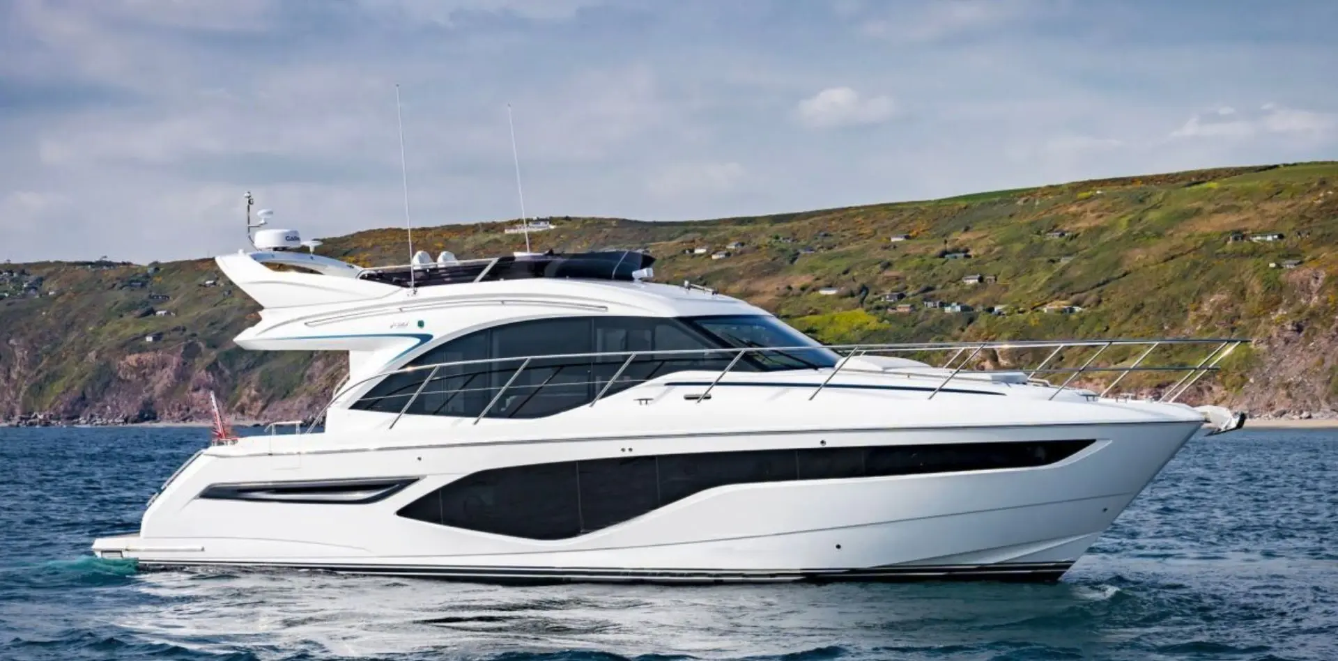 Princess 50 — Bateau à moteur blanc vu de profil dans une baie, sous un ciel nuageux.