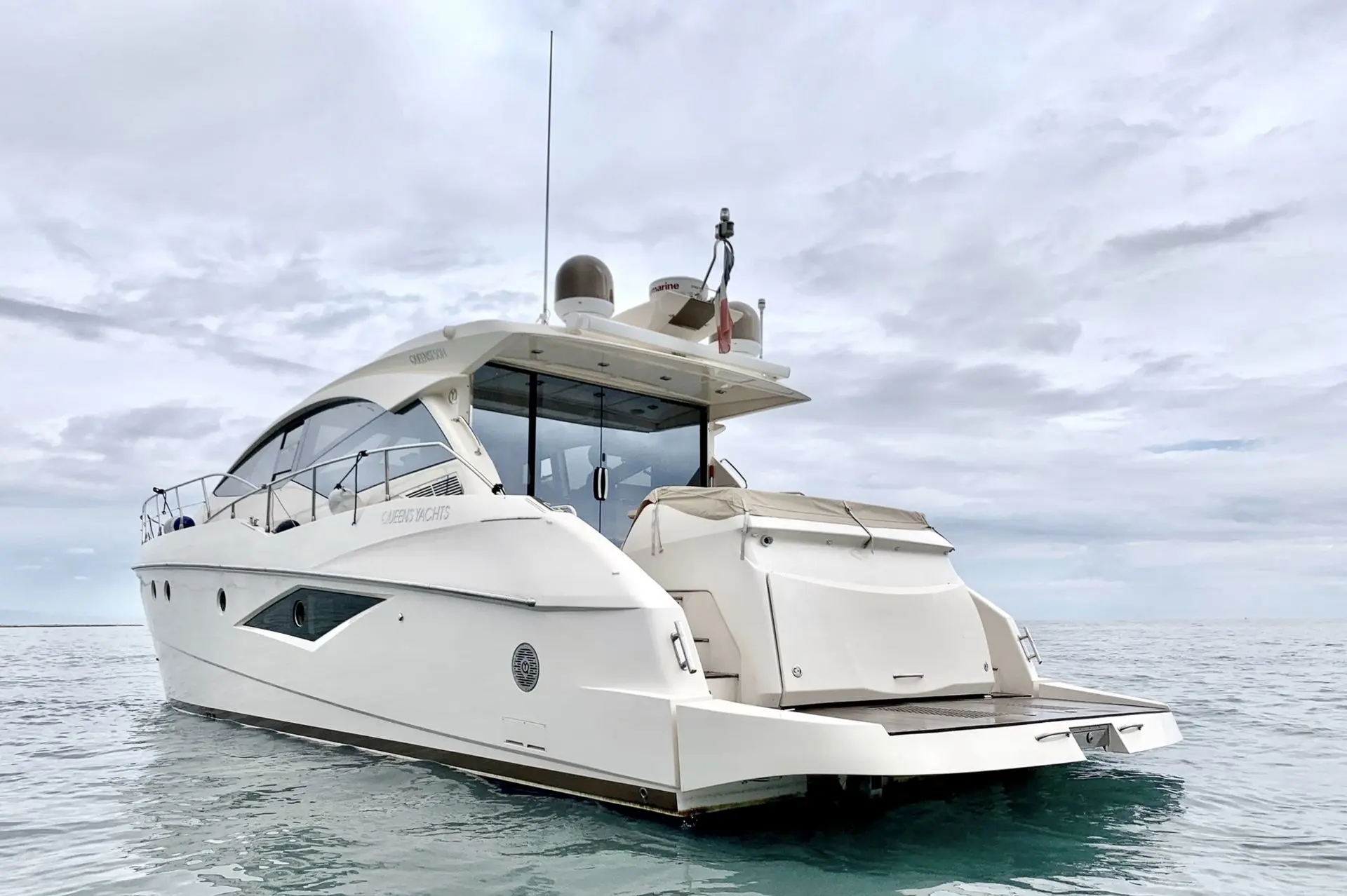 Queens Yachts 50 HT — Bateau à moteur blanc vu de trois quarts arrière sur une mer calme.