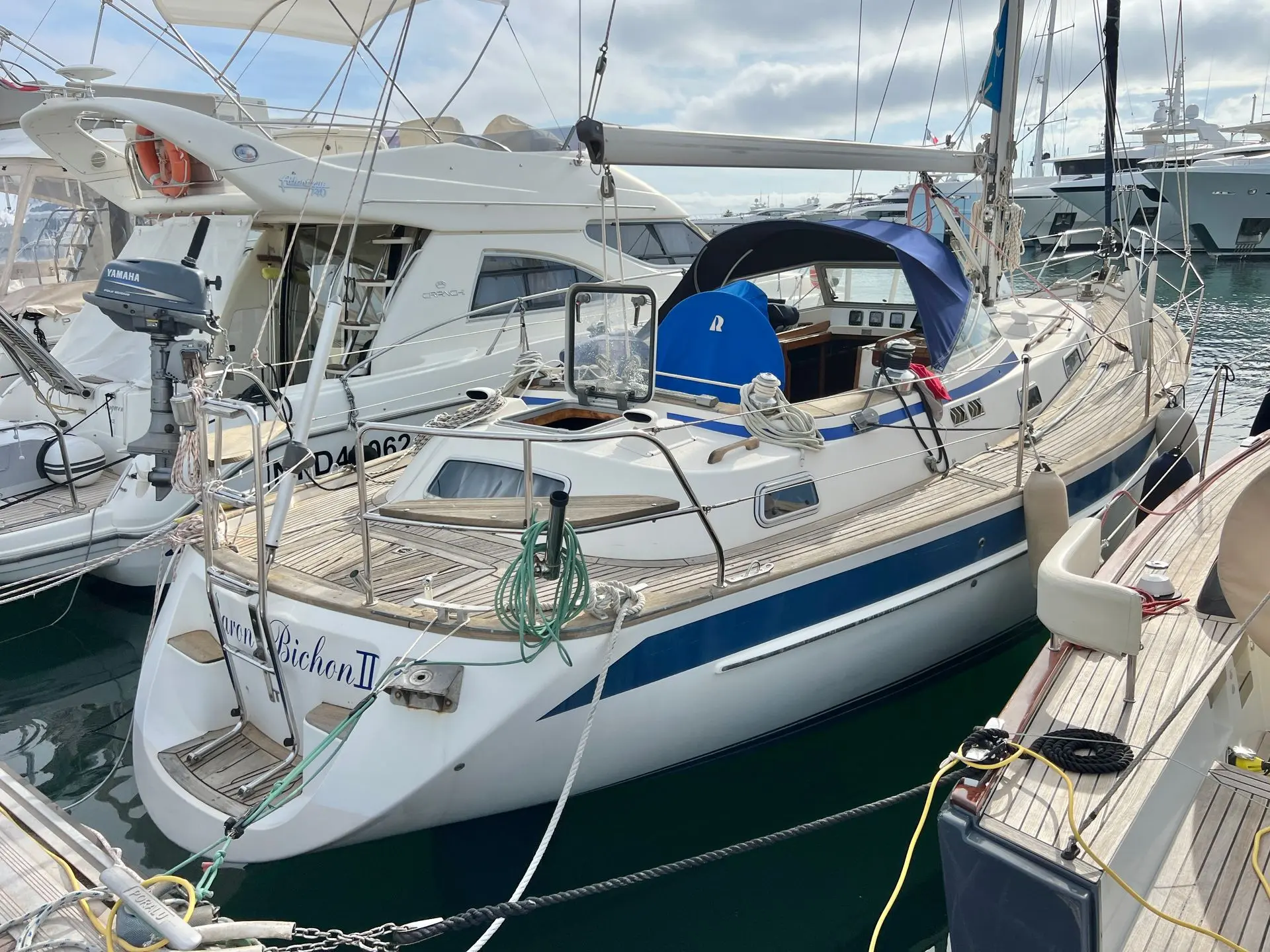 Hallberg Rassy 39 — Voilier blanc et bleu amarré dans un port, vu de trois quarts arrière.