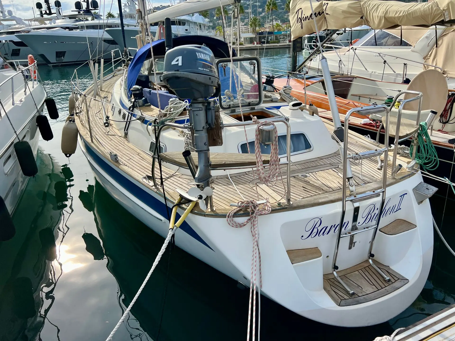 Hallberg Rassy 39 — Vue arrière trois-quarts d’un voilier amarré dans une marina, avec moteur hors-bord.