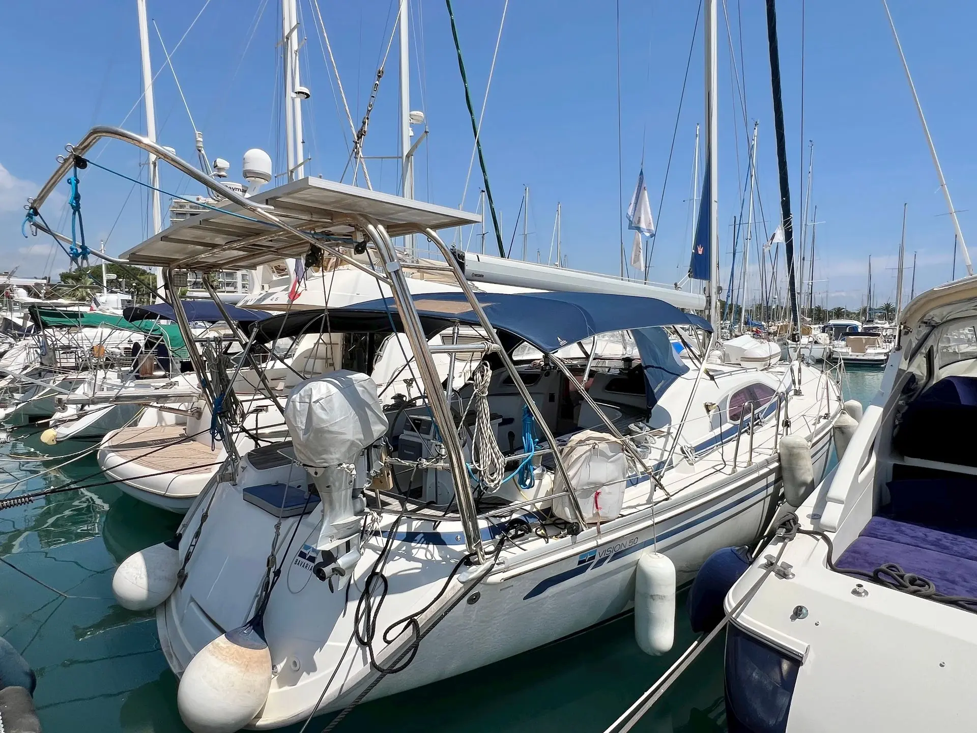 Bavaria 50 Vision — Voilier blanc amarré dans une marina, vu de trois quarts parmi d'autres bateaux.