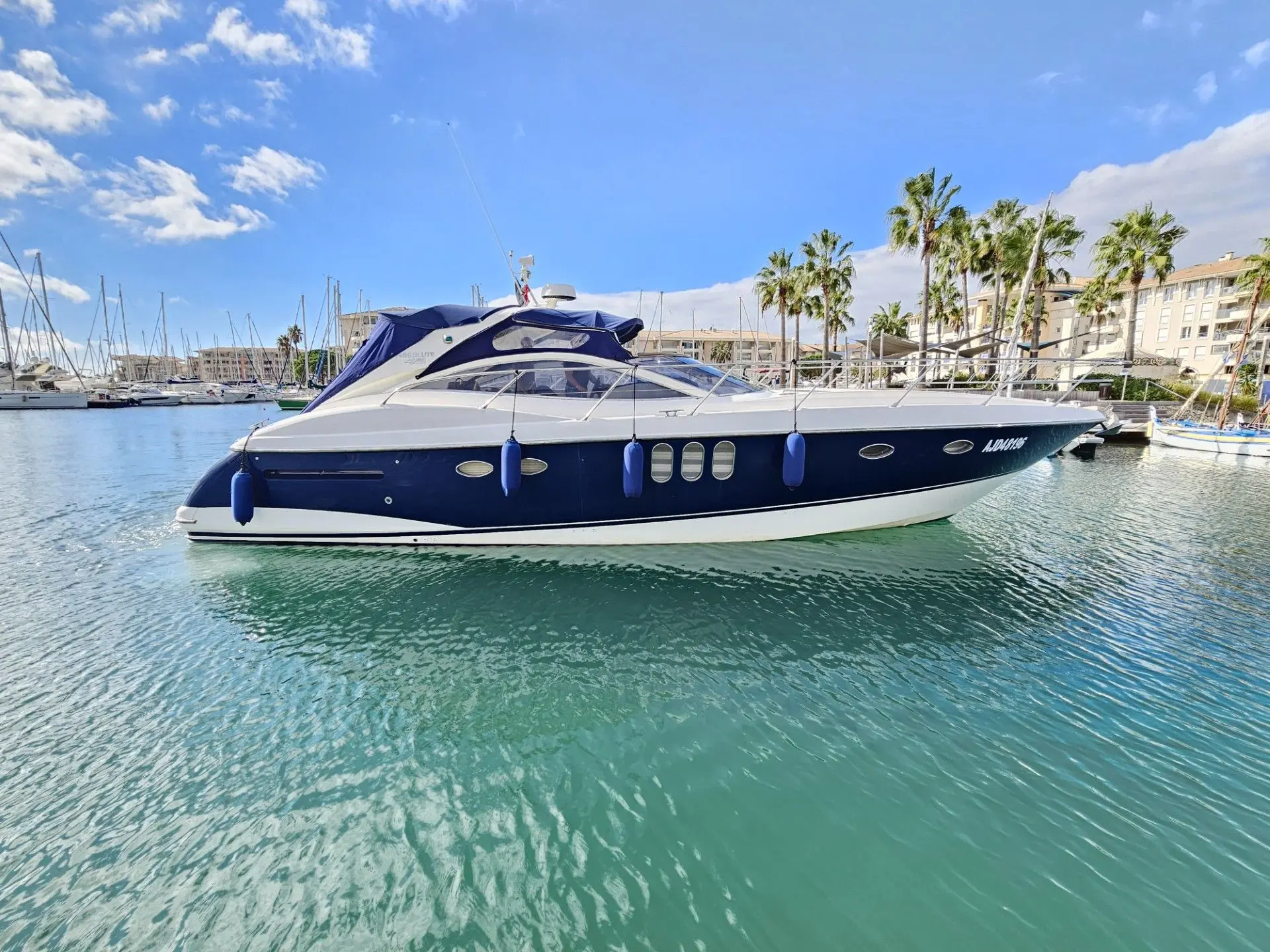 Absolute 45 — Bateau à moteur bleu et blanc vu de profil dans une marina ensoleillée.