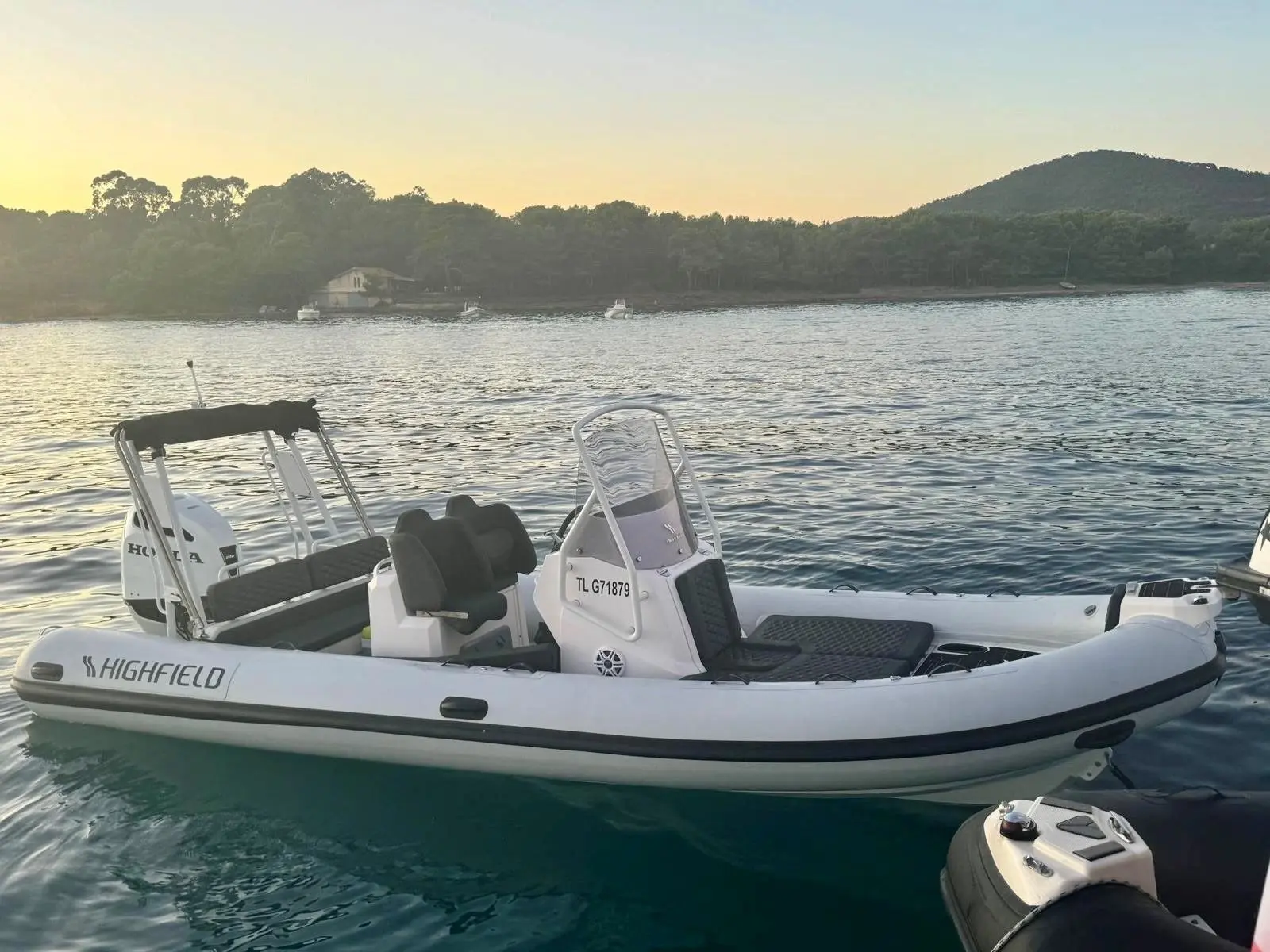 Highfield SPORT 660 — Semi-rigide blanc amarré sur une eau calme, photographié de profil au coucher du soleil.