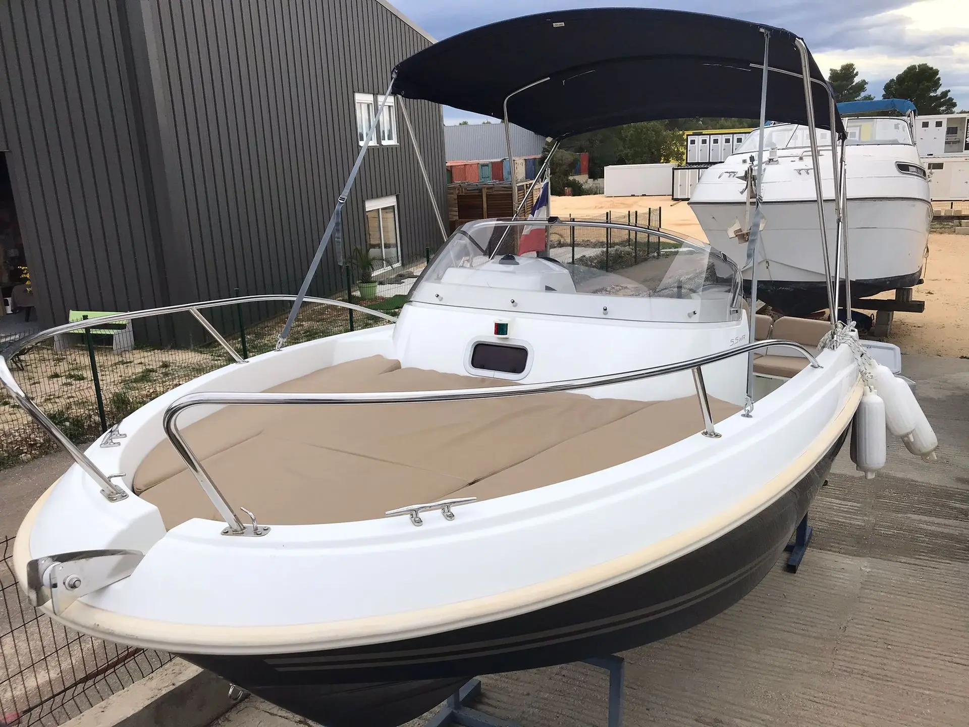 Jeanneau Cap Camarat 555 — Bateau à moteur blanc et noir vu de trois quarts avant, avec taud installé.