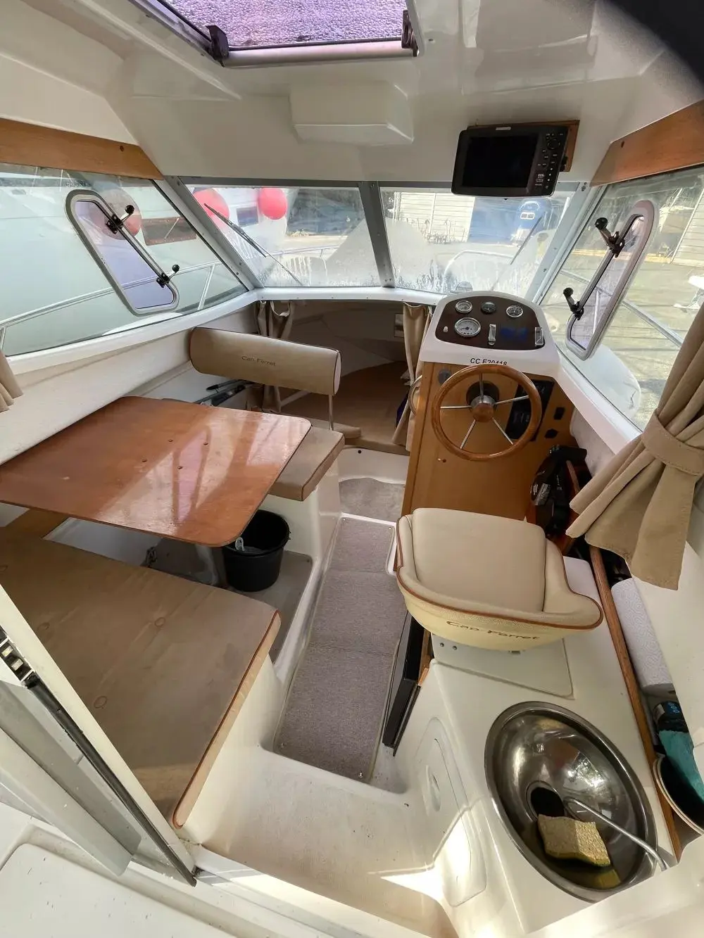 B2 Marine Cap Ferret 720 — Vue intérieure du poste de pilotage avec carré, table, évier et instruments.