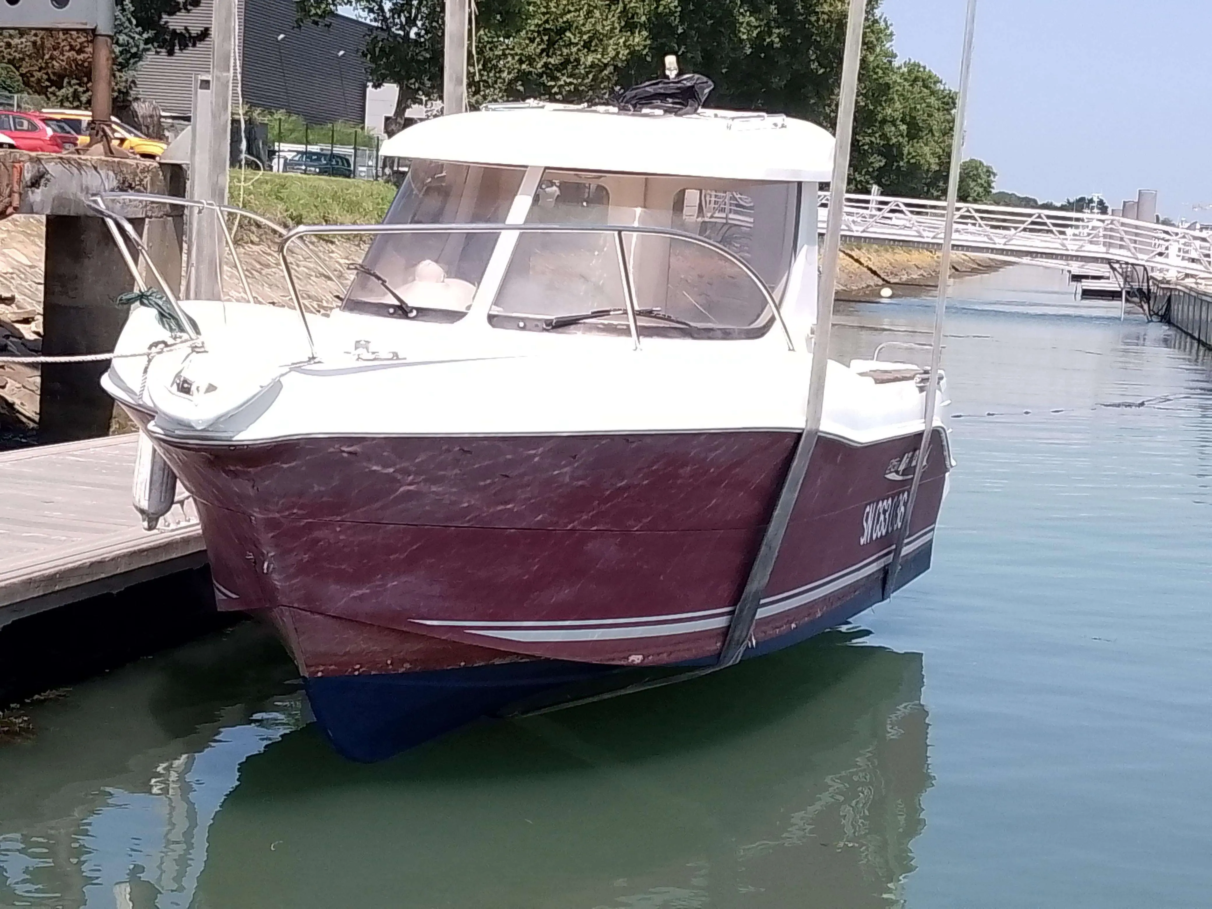 Arvor 215 — Bateau à cabine blanche et coque bordeaux amarré dans un port.